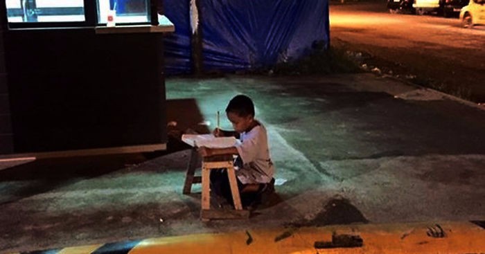 Bezdomny chłopiec odrabia wieczorami prace domowe przy użyciu światła z lokalnej restauracji McDonald’s.