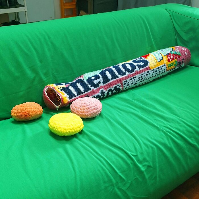 Crochet long cylindrical pillow and three round crochet cushions on green couch