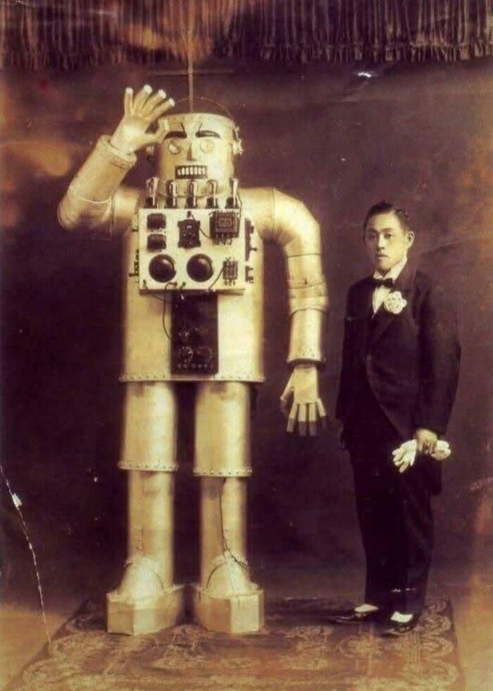 Retrofuturistic image of the past's imagined future: a man in a tuxedo standing next to a large robot.