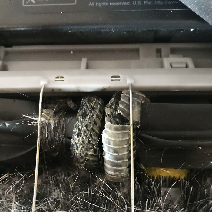 A close-up of a vacuum cleaner rollerbrush completely covered in tangled hair, a truly bizarre sight.