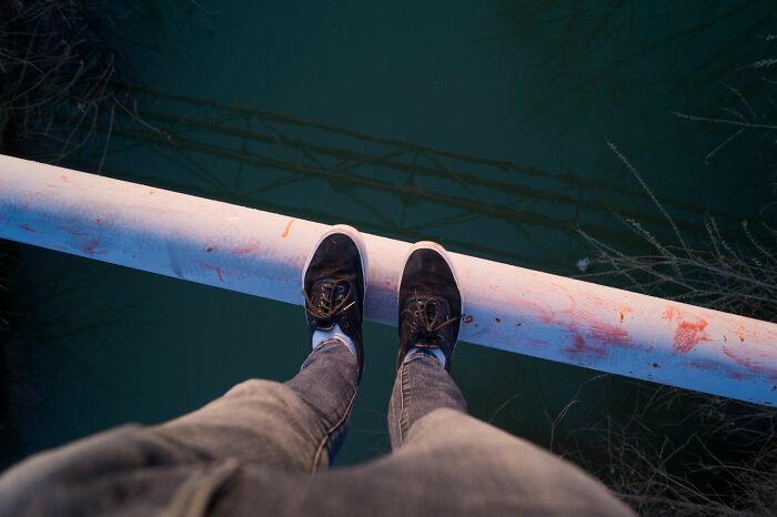 A person stands on a narrow ledge above water, symbolizing the precariousness of an airline seating lottery.