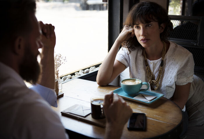 Woman listening intently to man during serious coffee shop conversation