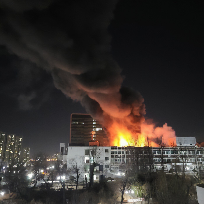 A truly bizarre, massive fire engulfing a building at night with thick smoke, making one wonder if they are hallucinating.
