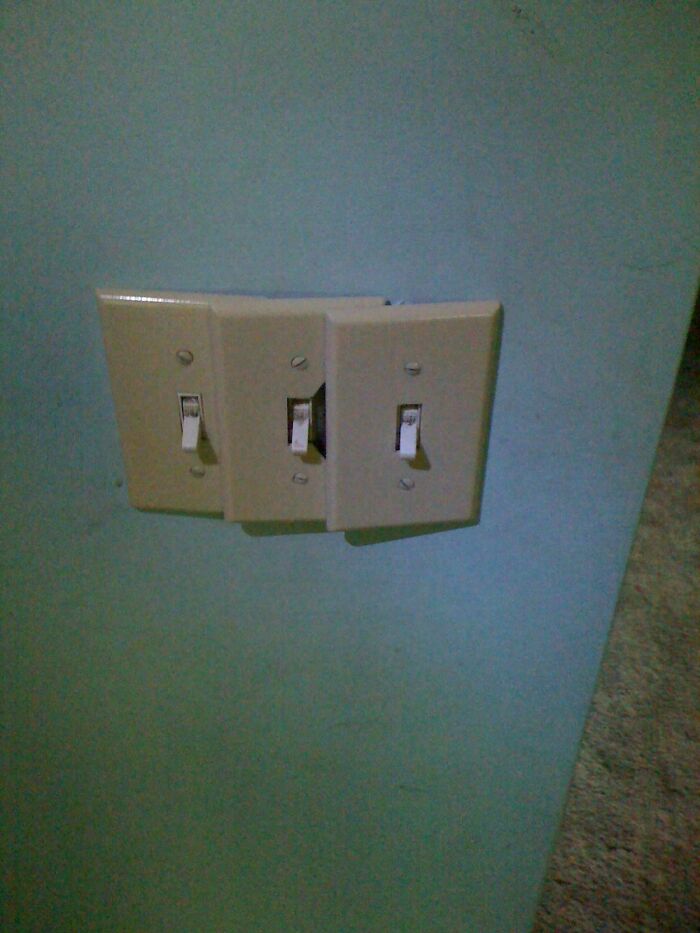 A poorly installed set of three light switches on a blue wall, showing a DIY fail due to misaligned skills.