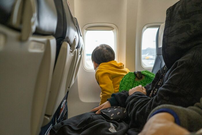 A young child looking out a plane window, hinting at unhinged moments cabin crew sometimes face.