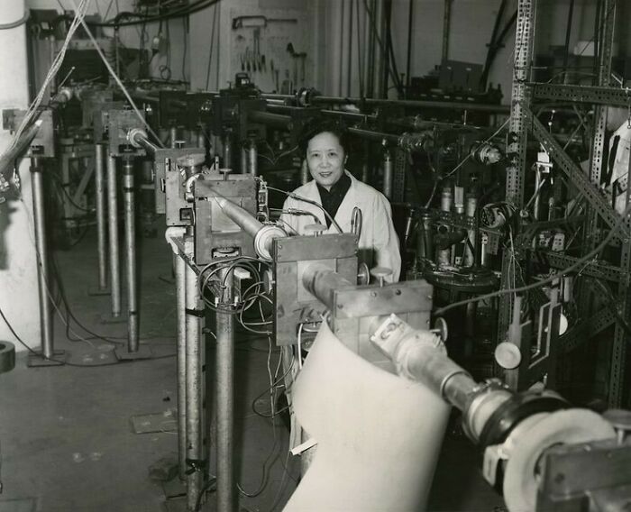 A black and white photo of Chien-Shiung Wu, a pioneering physicist, standing in a laboratory filled with scientific equipment, embodying Women in History.