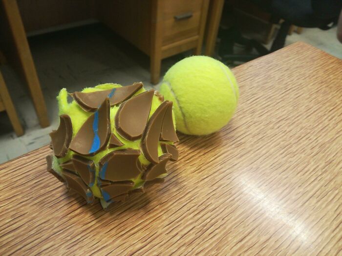A tennis ball covered in chocolate shards, next to another tennis ball, representing forbidden foods.