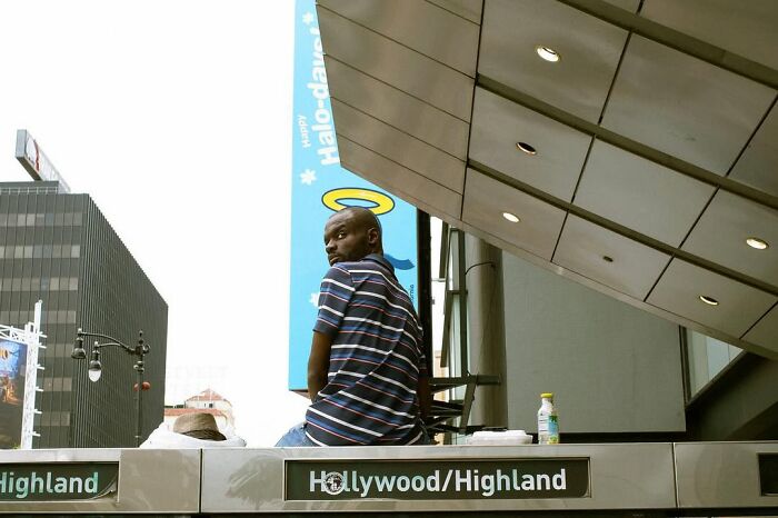 Jeremy Paige captures a perfectly timed street photo of a man sitting under a modern overhang at Hollywood/Highland.