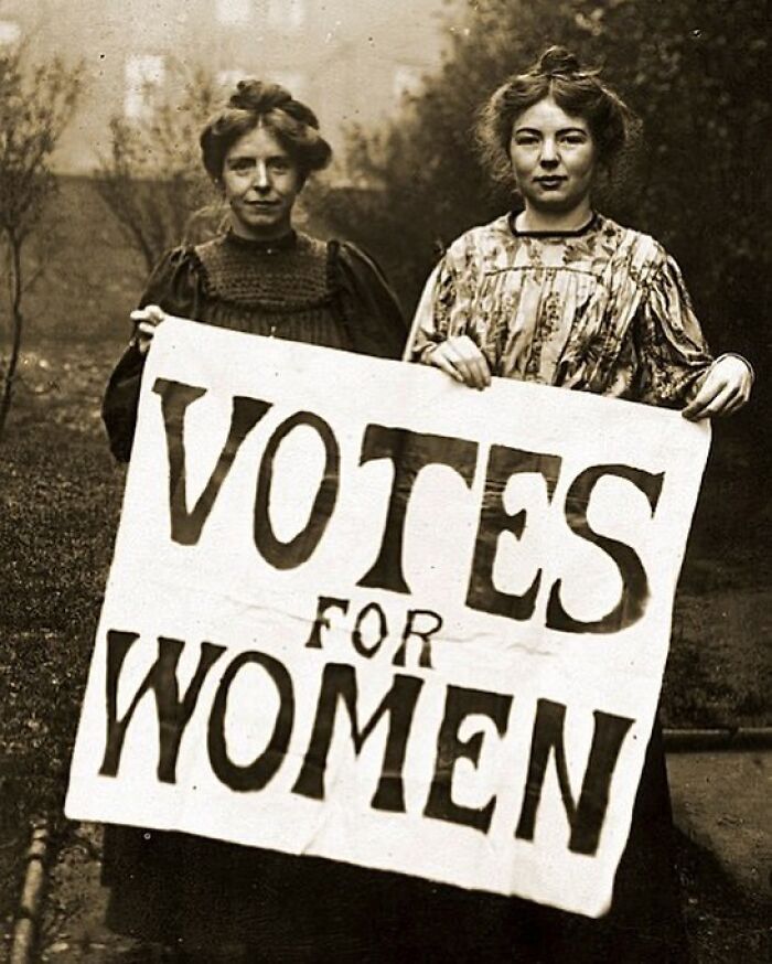 Two determined women in history hold a Votes for Women suffrage sign, advocating for womens rights.