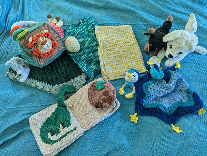 Collection of colorful crocheted toys and blankets laid out on blue fabric