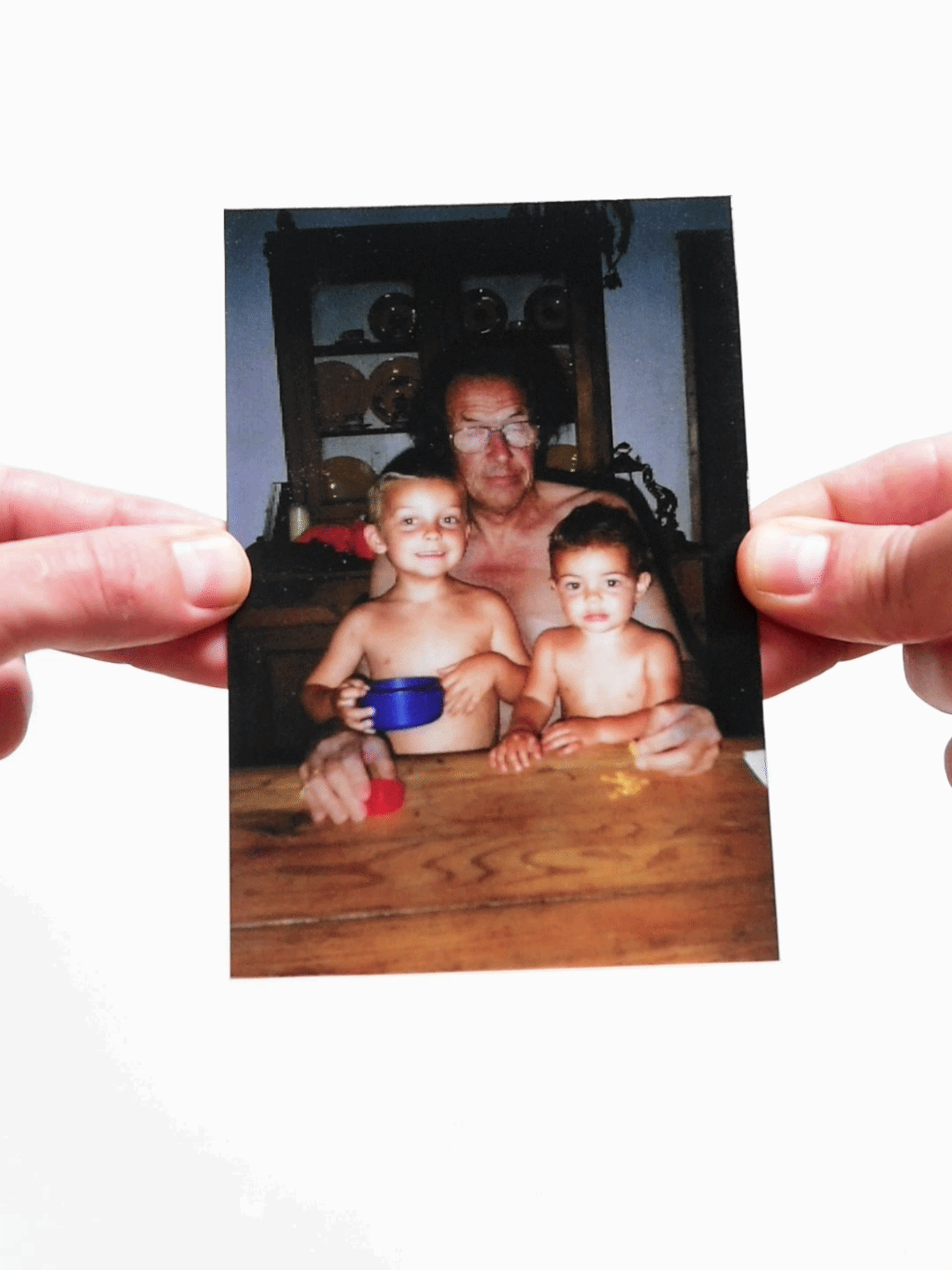Shirtless father with two small children sitting at a wooden table
