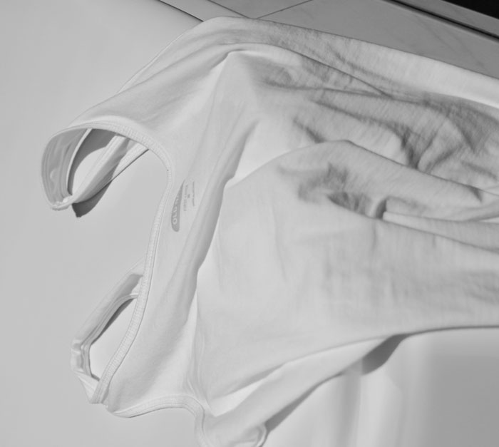 White tank top laid flat on a surface with soft shadows