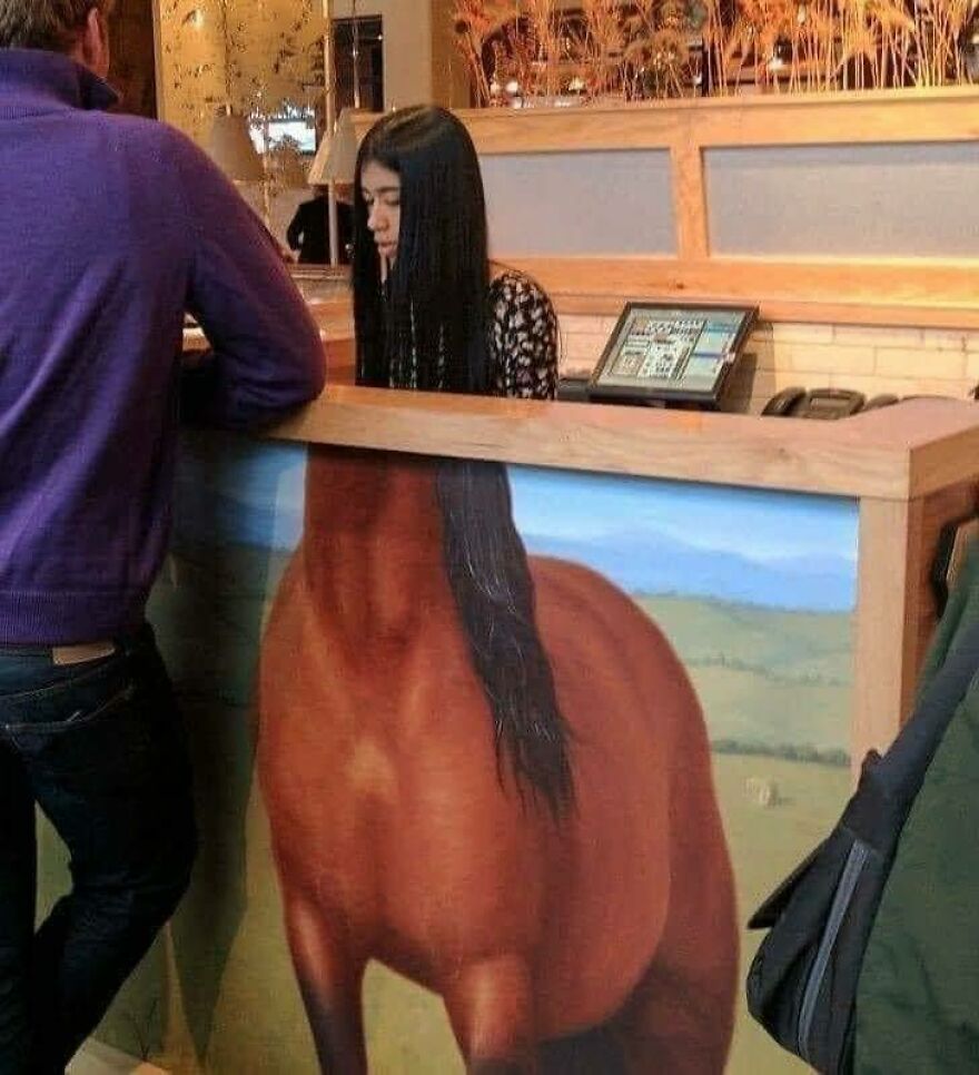 A woman behind a counter that features a painting of a horse's body, creating a chaotic and disturbing pic.