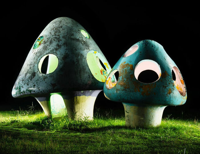 Surreal Japanese playgrounds at night, two mushroom-shaped structures with glowing windows on grassy ground, by Fujio Kito.