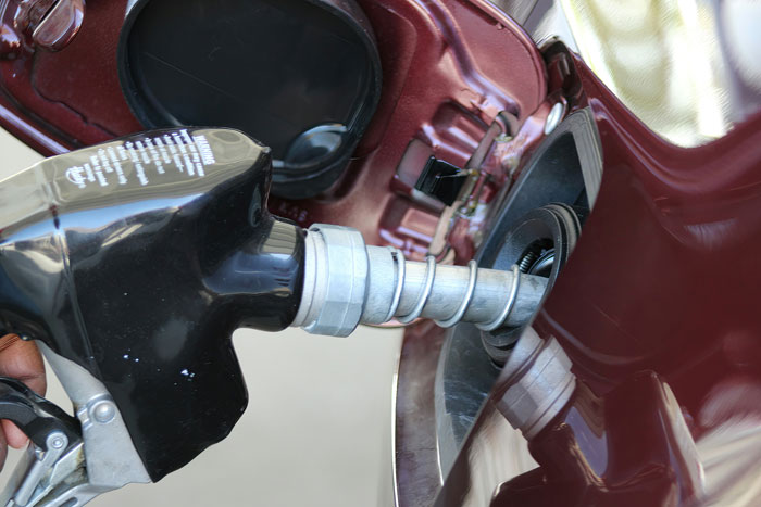 Fuel nozzle filling gas tank of a red car at gas station