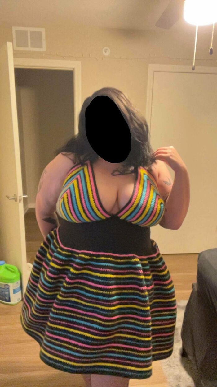 Woman wearing a colorful striped crocheted dress showcasing talented crocheters' work
