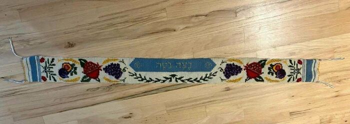 Narrow crocheted band with floral pattern on wooden floor