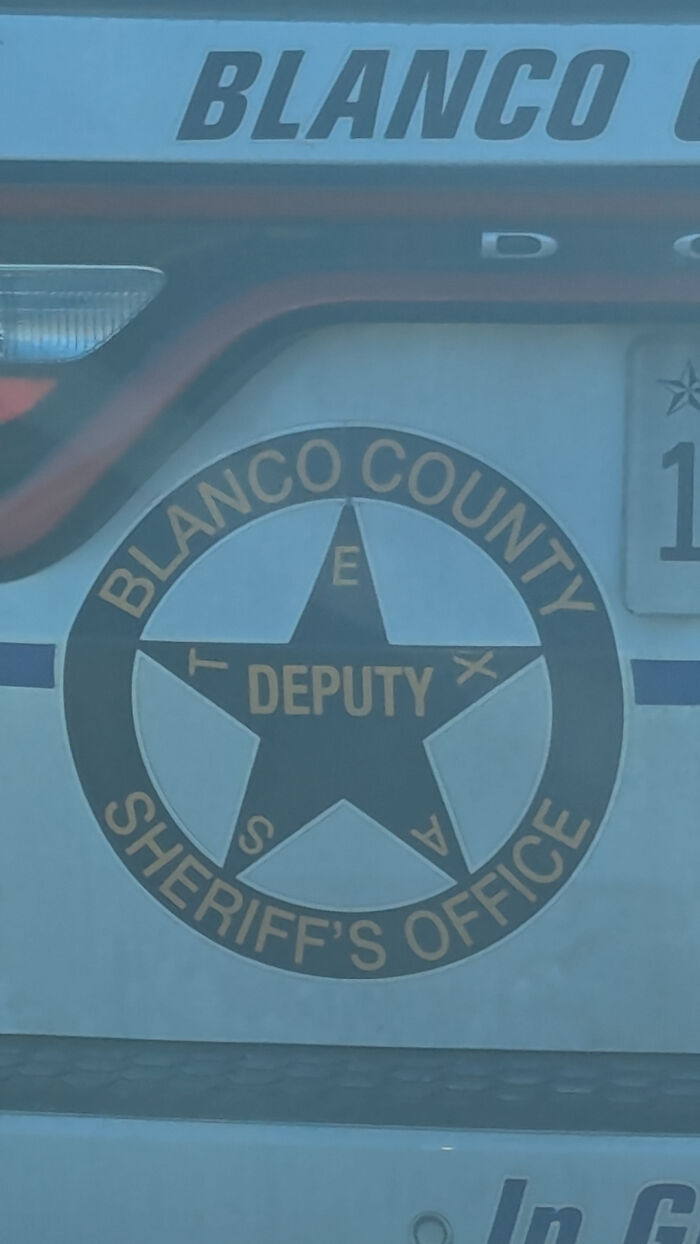 A Blanco County Sheriff's Office deputy emblem on a police car, a design fail with scattered letters.