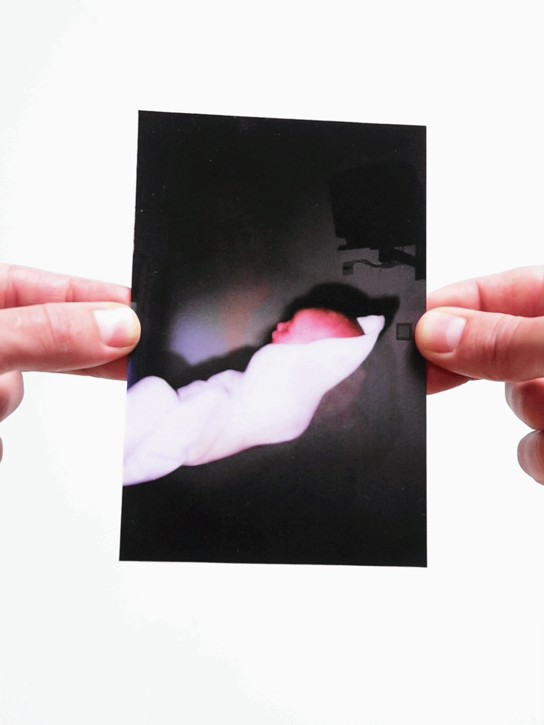 Newborn baby wrapped in white blanket in a dimly lit hospital room