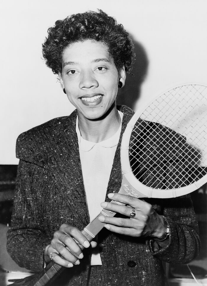 Althea Gibson, a groundbreaking athlete among women in history, holding a tennis racket.