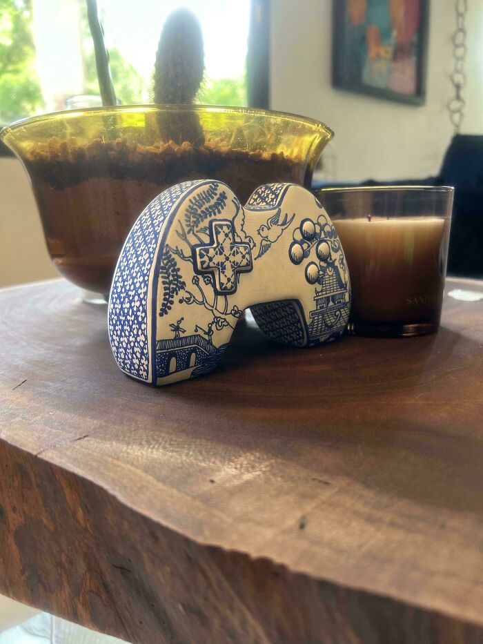 Hand-painted gaming controller with blue pattern near a candle and indoor plant