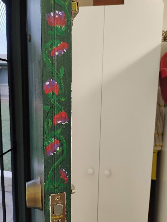 Close-up of painted flowers on green door frame near door latch
