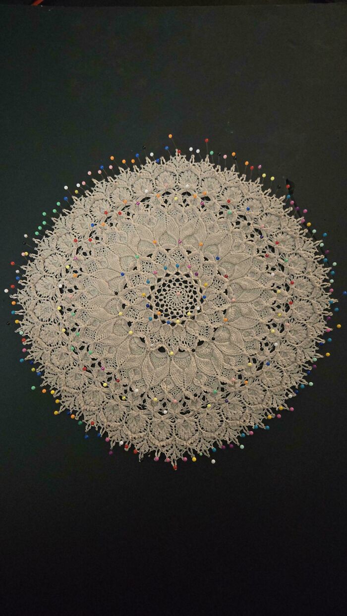 Circular crochet lace doily pinned to a flat surface for blocking