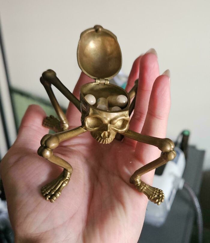 Small brass skeleton frog bag opened showing pills inside