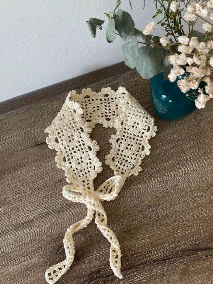 Delicate cream crocheted lace collar on wooden table