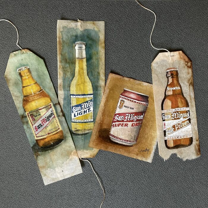 Detailed miniature paintings of beer bottles and a can on used tea bags by artist Ruby Silvious.