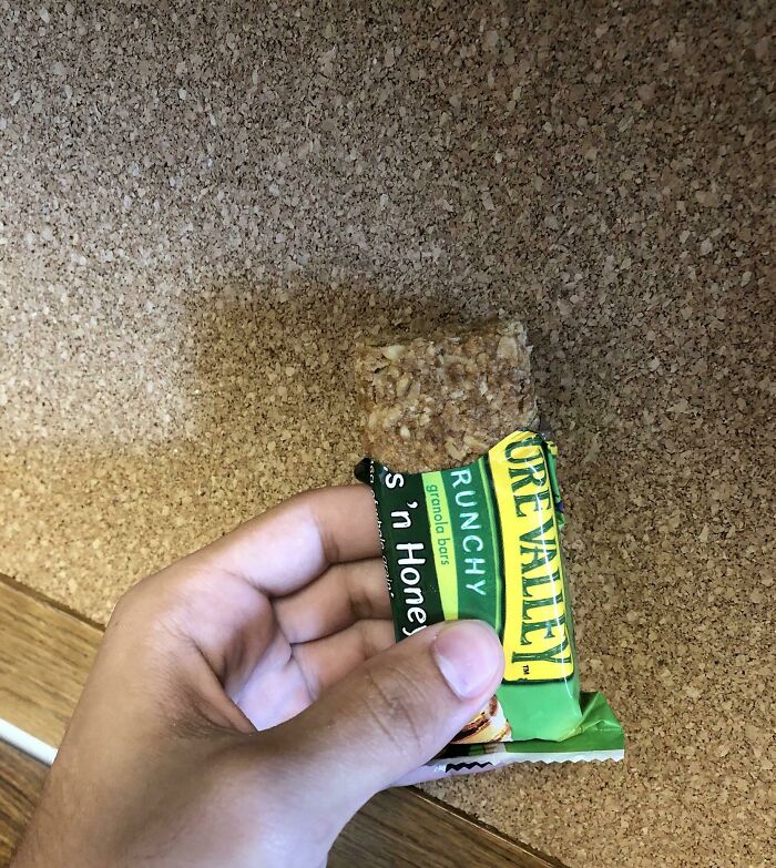 A hand holds a partially unwrapped granola bar, appearing as forbidden food.