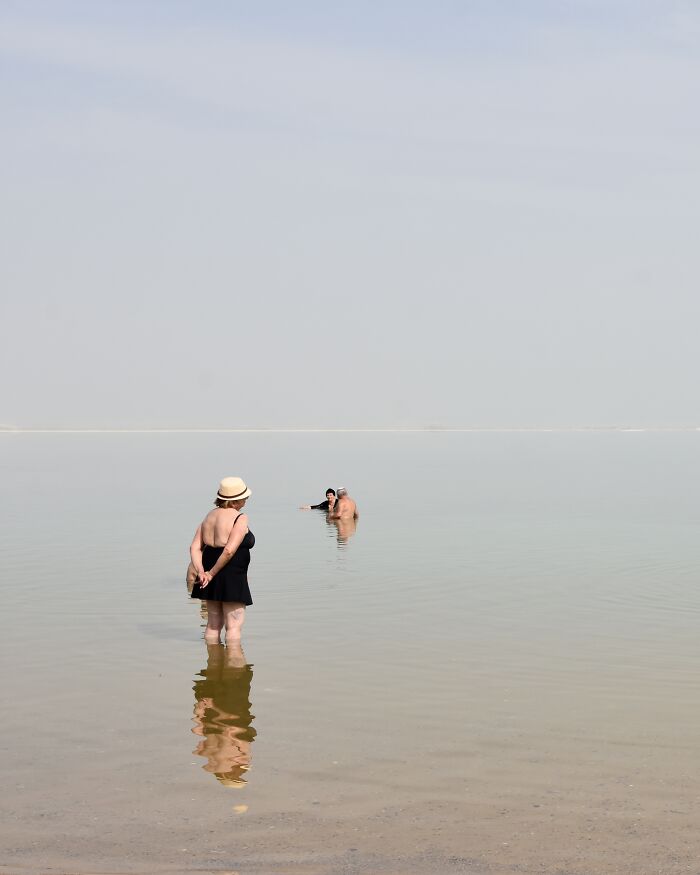 A photographer uses negative space to capture people in water on a minimalist beach scene.