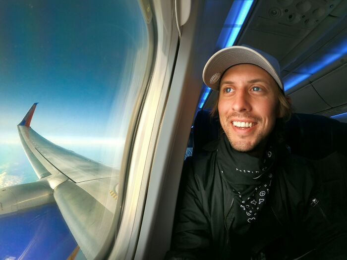 A happy passenger looking out a plane window, a common sight for cabin crew.