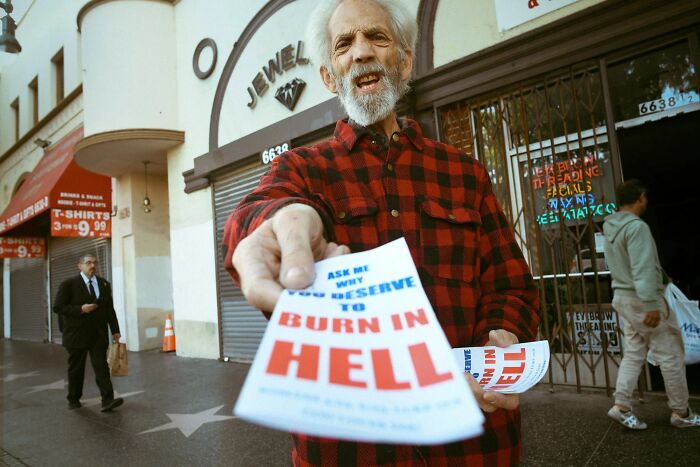 Jeremy Paige captures a perfectly timed street photo of an elderly man holding flyers on Hollywood Boulevard.