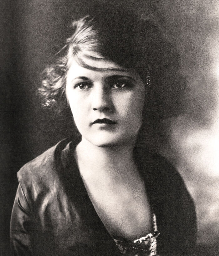A black and white portrait of a young woman with short, wavy hair, looking forward, showcasing an influential woman in history.