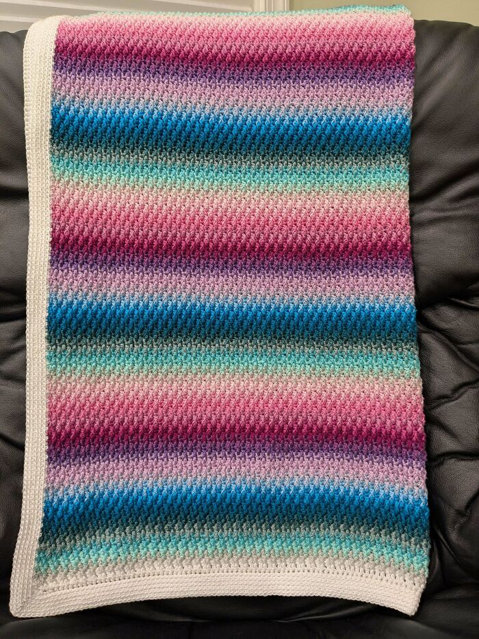 Striped crocheted blanket in pink, blue, and turquoise tones