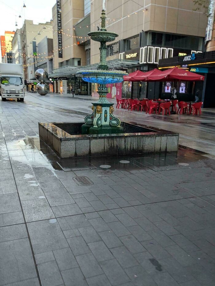 Hilariously unhinged design fails: A small fountain in a city street, appearing to spill water onto the surrounding pavement.