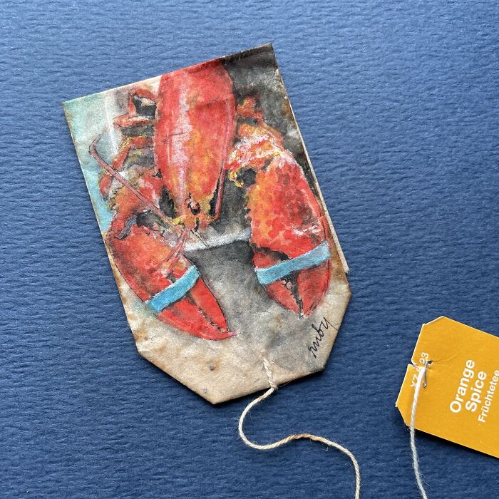 A red lobster painted on a single used tea bag by artist Ruby Silvious.