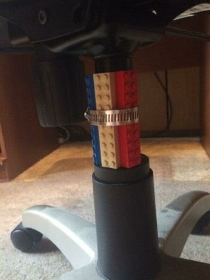 A DIY fail of an office chair height adjusted with colorful Lego bricks and a metal clamp.