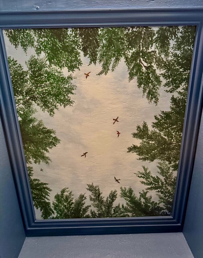 Ceiling painting of sky with birds and leafy branches in frame