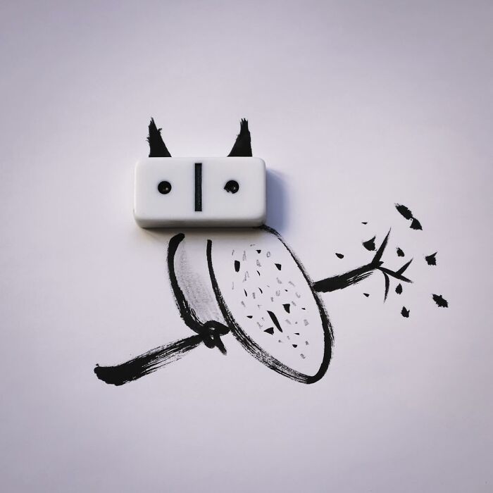 A playful illustration of an owl sitting on a branch, with a white domino used as its eyes