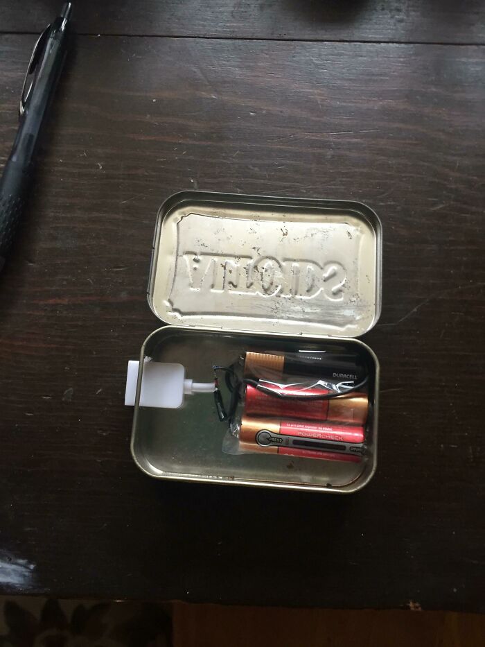 A DIY fail: a mint tin containing several batteries and a charging cable, poorly assembled.