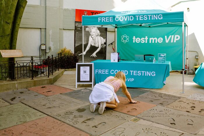 A woman crouches on the Hollywood Walk of Fame, a perfectly timed street photo by Jeremy Paige.