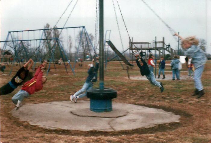 Children swinging dangerously fast on a spinning playground ride, demonstrating playground fails.