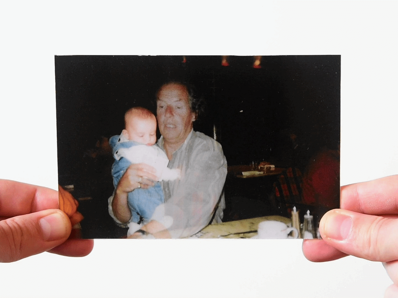 Photo of an elderly man holding a baby indoors