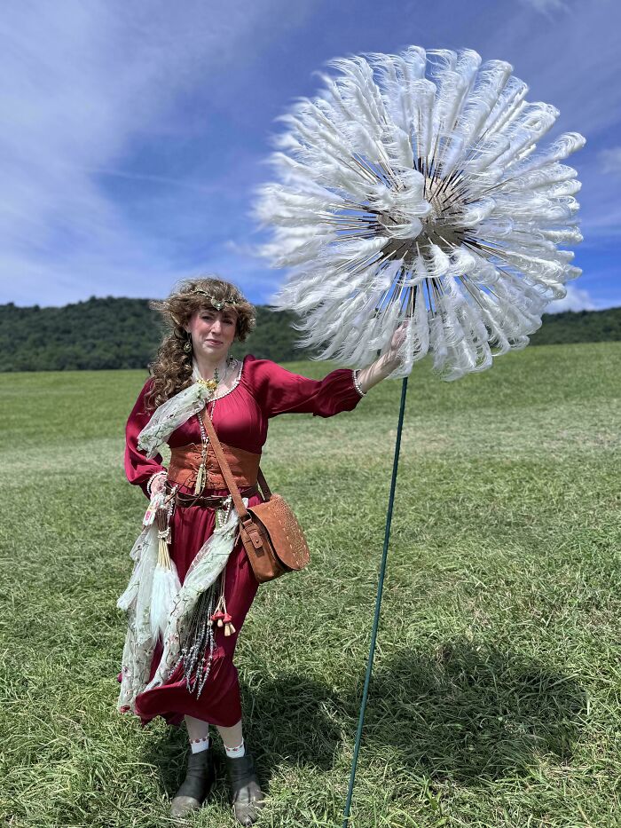 Woman in red dress holding large artistic dandelion in green field quirky projects
