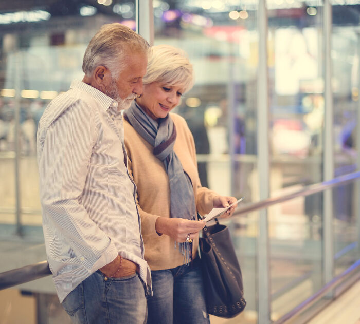 A senior couple checking their airline seating lottery tickets at the airport, preparing for their flight.
