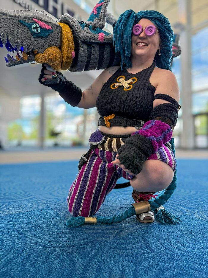 Cosplayer wearing intricate crocheted costume with large weapon