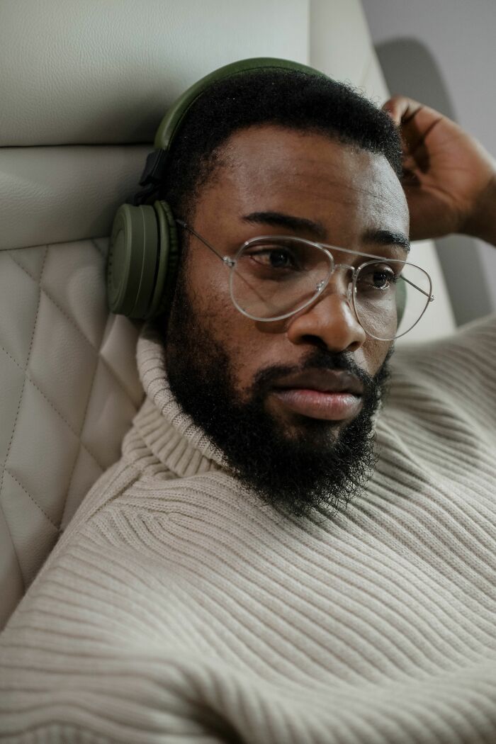 A man with glasses and headphones on a plane, portraying entitled people getting a reality check.