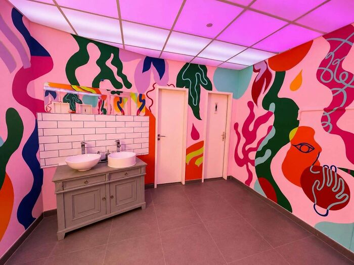 Bathroom with colorful abstract murals and pink ceiling lighting